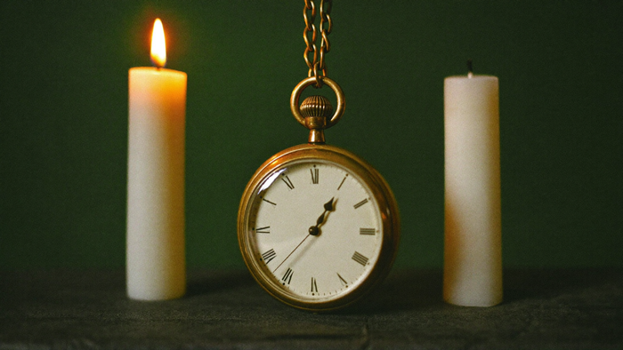 Goldene Taschenuhr zwischen zwei Kerzen im Kerzenlicht – Spiegelstunde 20:20 Uhr