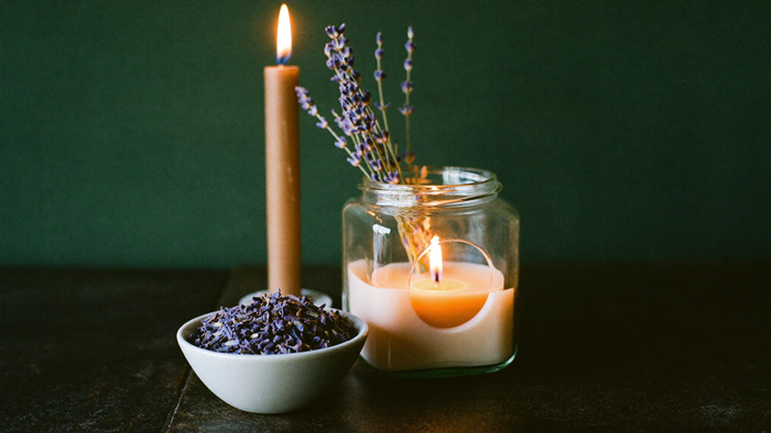 Brennende Kerzen mit frischem Lavendel und einer Schale getrockneter Lavendelblüten