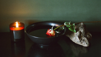 Schwarze Wasserschale, Obsidian und welkende Rose im Kerzenlicht — Symbolbild für die dunkle Nacht der Seele