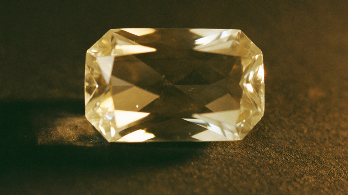 Facettierter hellgoldener Topas im Kerzenlicht auf dunklem Schiefer