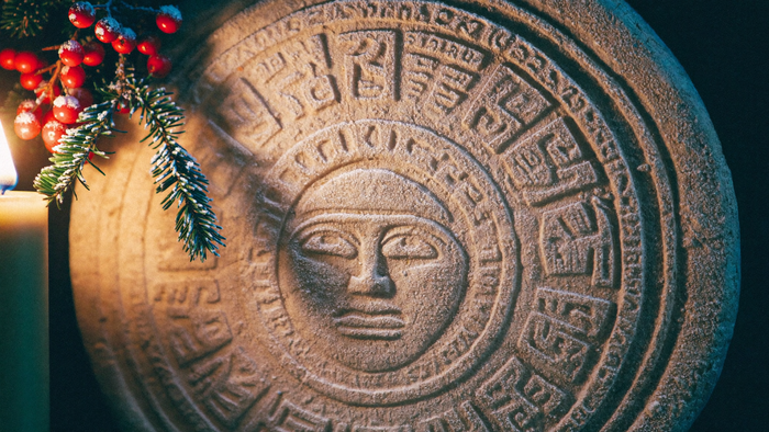Bereifter Maya-Kalenderstein mit Tannenzweig und Stechpalme im Kerzenlicht – Portaltage Dezember 2027