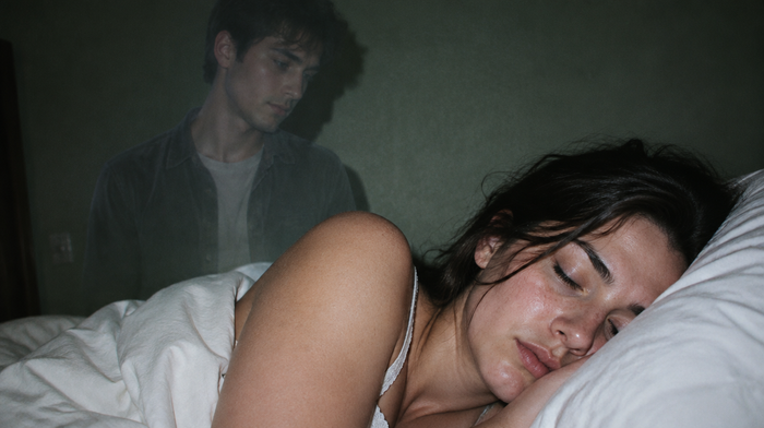 Schlafende junge Frau im Bett, hinter ihr die blasse Gestalt eines jungen Mannes wie eine Erinnerung im Traum