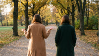 Zwei Frauen gehen im Herbst von hinten gesehen durch einen Park und sprechen miteinander – traumasensible Beratung in München