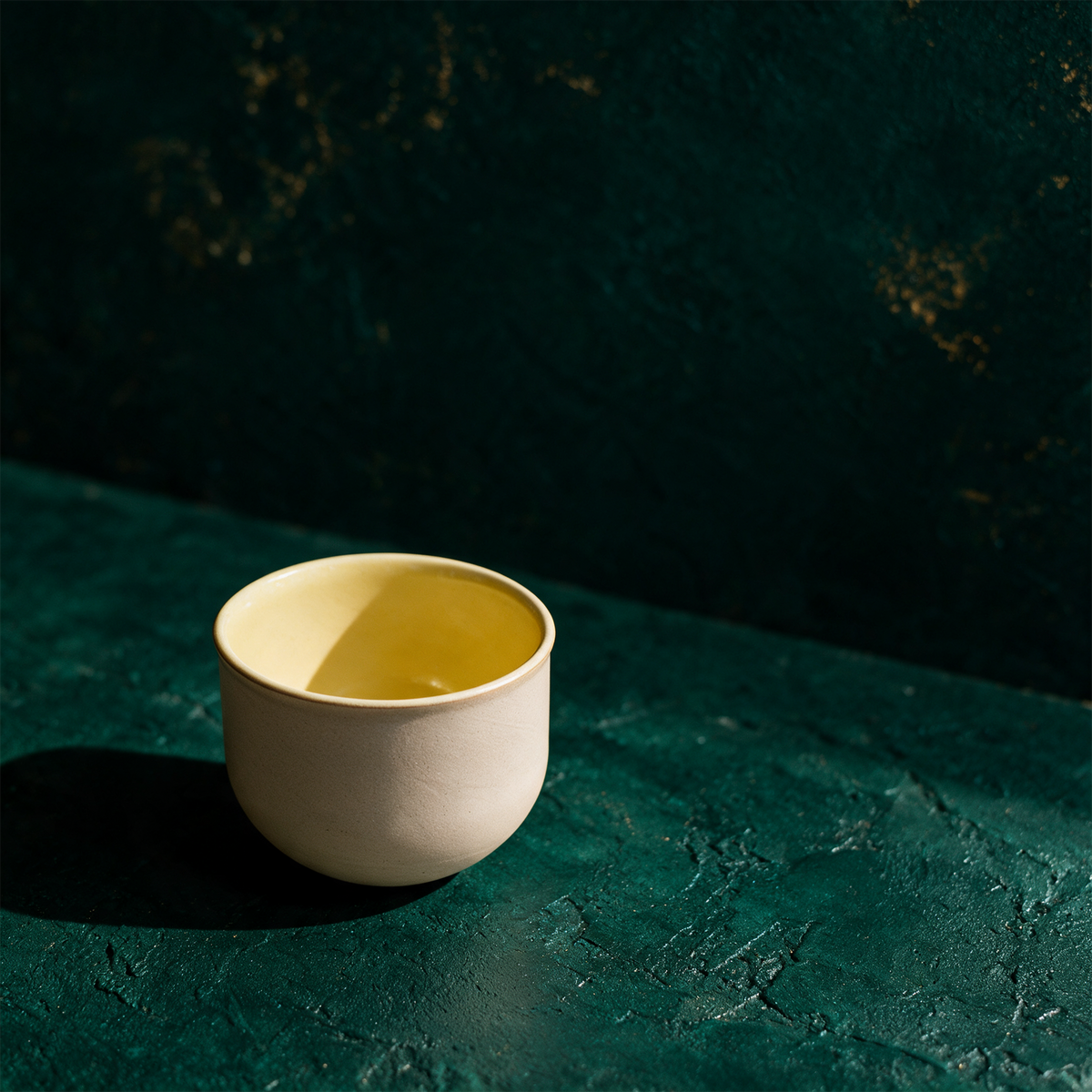 OCHA Teetasse gelb – alternative Produktansicht vor tiefem Smaragdgrün
