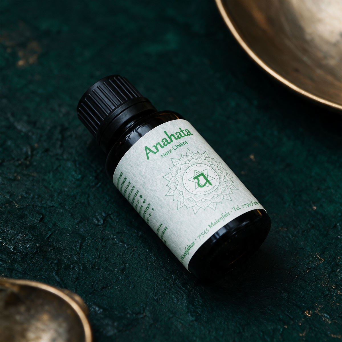Anahata Chakraöl neben Rosenquarz und Jade auf dunklem Stein