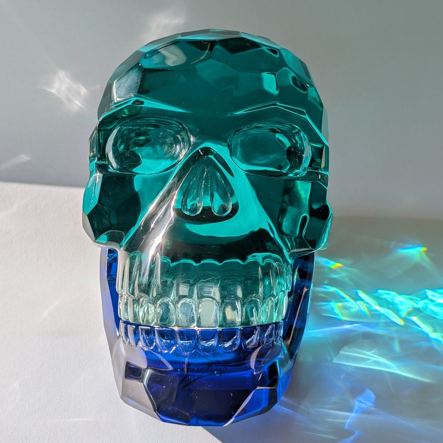 Monumentaler Kristallschädel (7.5kg) aus facettiertem blaugrünem Glas mit beweglichem Unterkiefer im Lichtspiel.