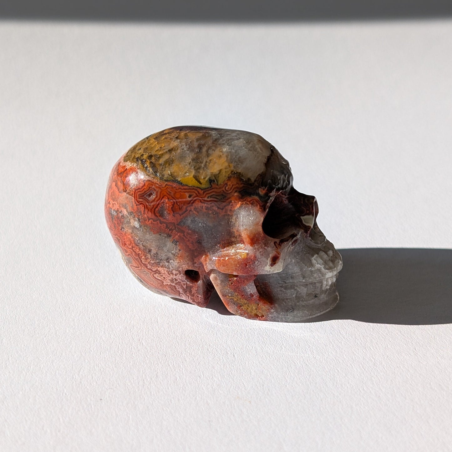 Kleiner Kristallschädel "Marjaana" (79g) aus bunt gebändertem Crazy Lace Achat.