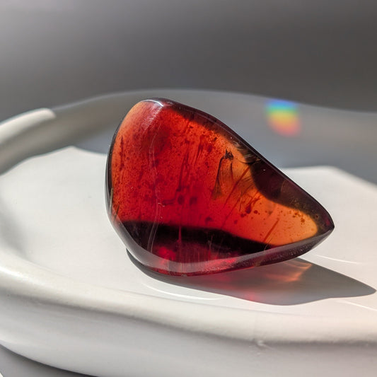 Bernstein Talisman "Rubin der Vorzeit" in dunkler, tropfenartiger Form mit rotem Kern.