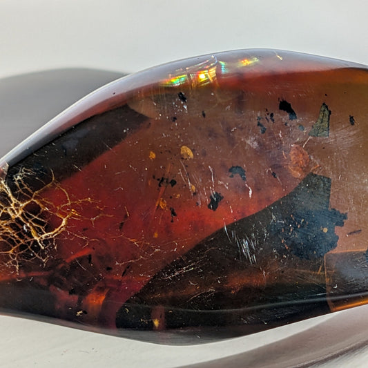 Bernstein Unikat "Das Blatt der Vorzeit" in dunkler, flammenartiger Form mit rotem Kern.