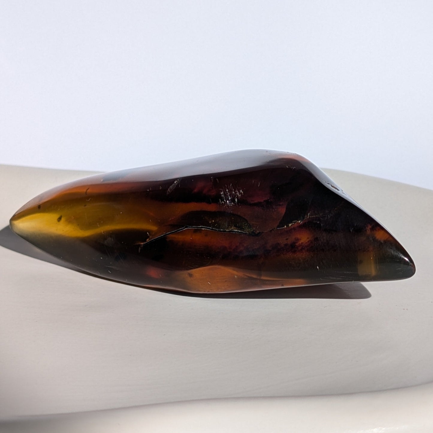 Bernstein Unikat "Das Blatt der Vorzeit" in dunkler, flammenartiger Form mit rotem Kern.