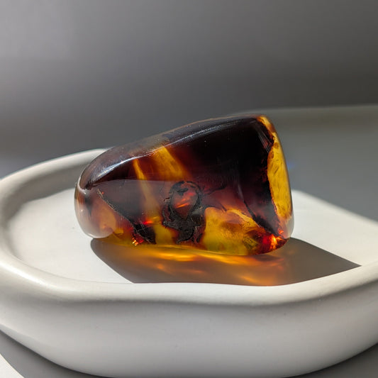 Bernstein Unikat "Das Herz des Waldes" in dunkler, unregelmäßiger Form mit rotem Kern.