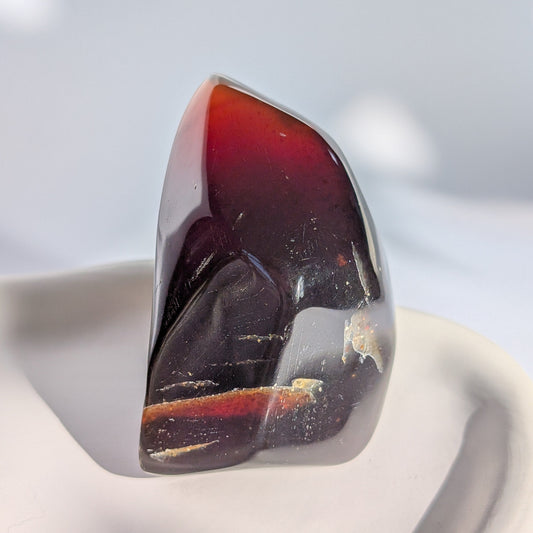 Bernstein Unikat "Die Flamme der Vorzeit" in dunkler, flammenartiger Form mit rotem Kern.