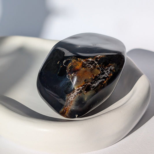 Bernstein Unikat "Fenster zur Vorzeit" in dunkler Farbe mit rotem Kern.