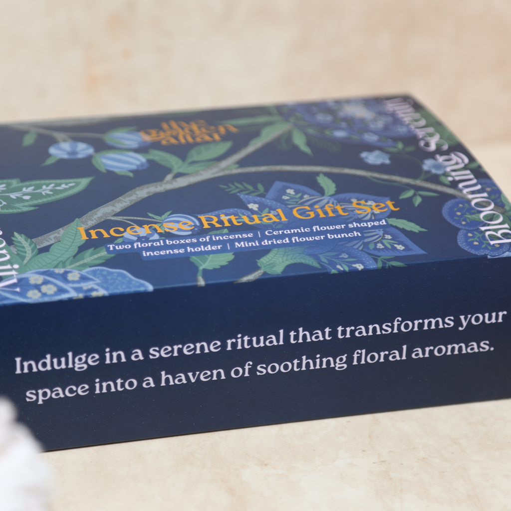 Das Ritual-Set 'Garten der Seele' von The Golden Altar mit zwei Räucherpackungen, einem blumenförmigen Keramikhalter und Trockenblumen in einer blauen Geschenkbox.