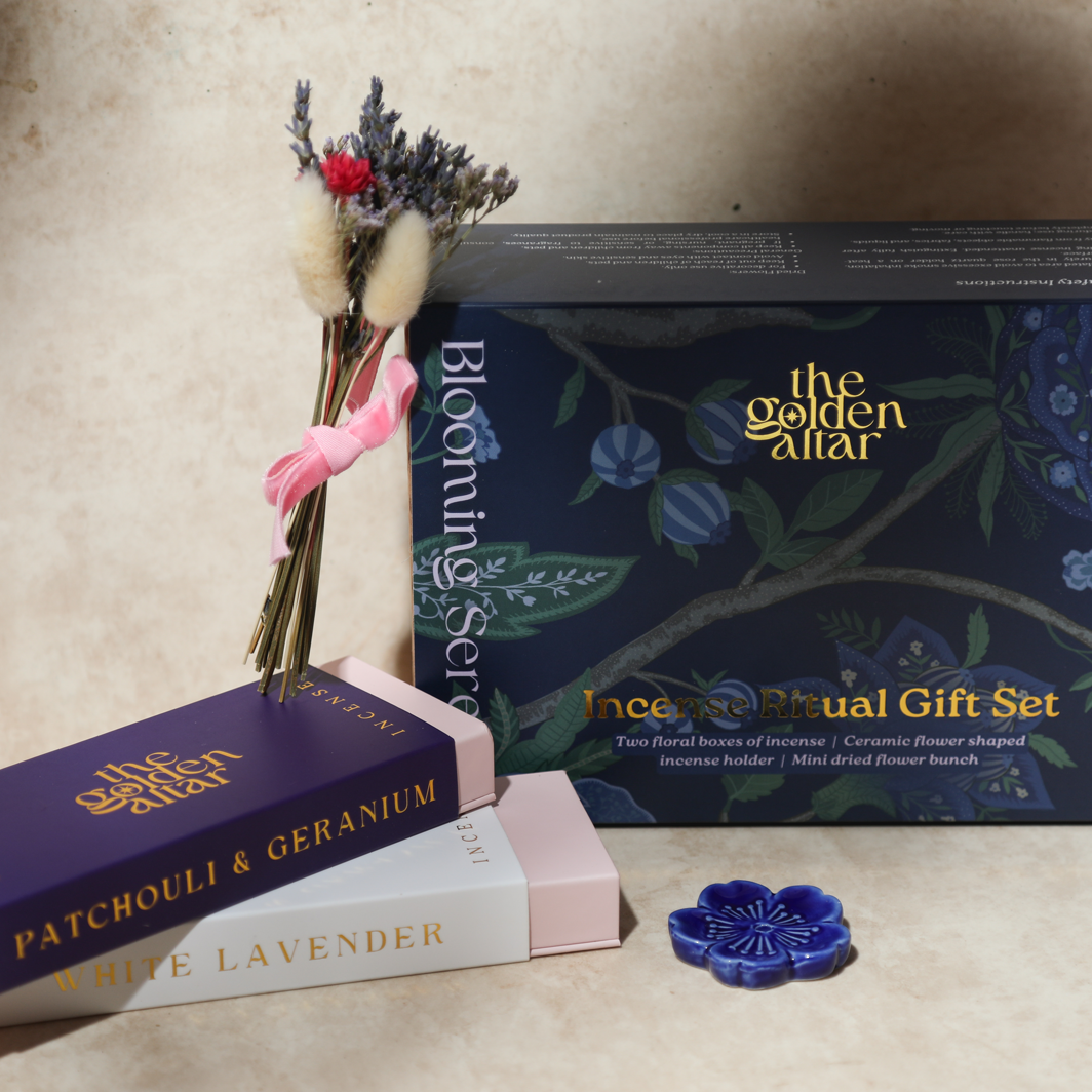 Das Ritual-Set 'Garten der Seele' von The Golden Altar mit zwei Räucherpackungen, einem blumenförmigen Keramikhalter und Trockenblumen in einer blauen Geschenkbox.