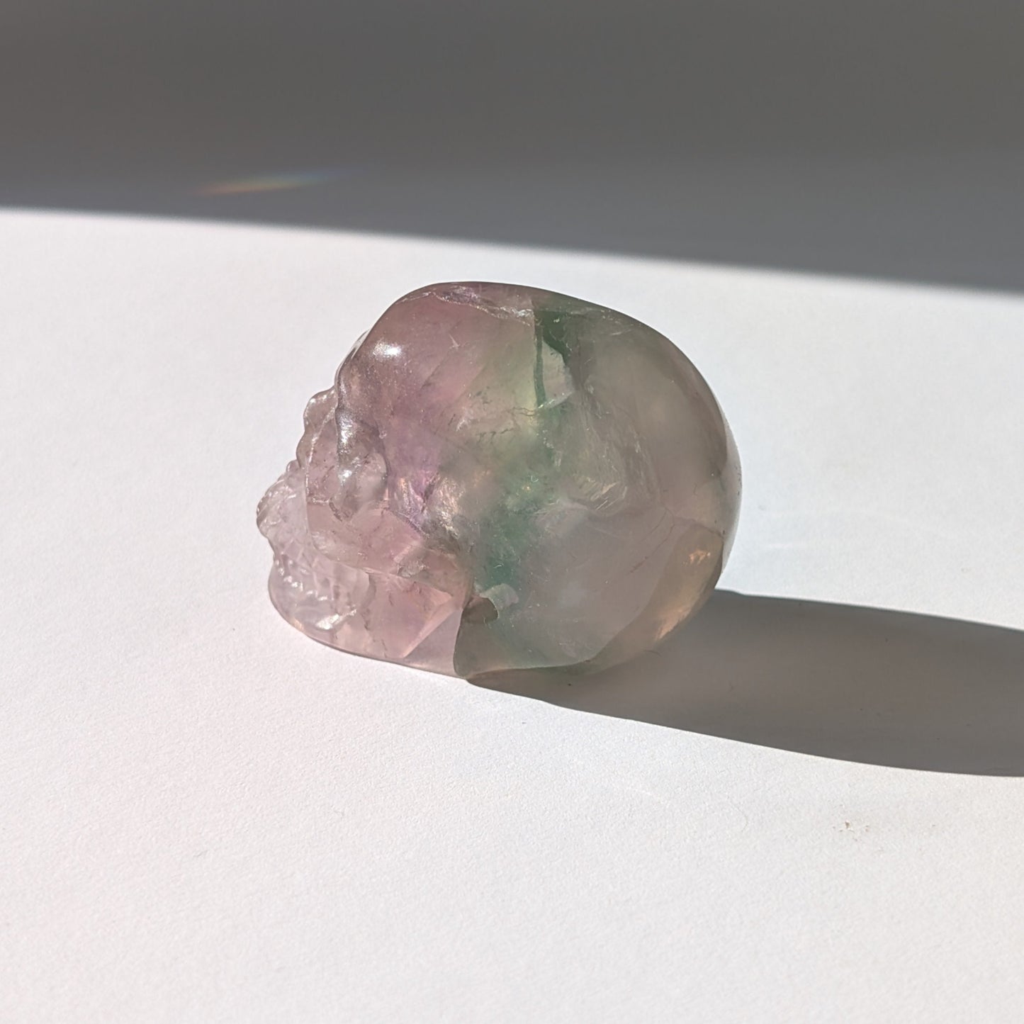 Ein 103g schwerer, handgeschnitzter Kristallschädel 'Uthar' aus durchscheinendem, grün-violettem Regenbogenfluorit.