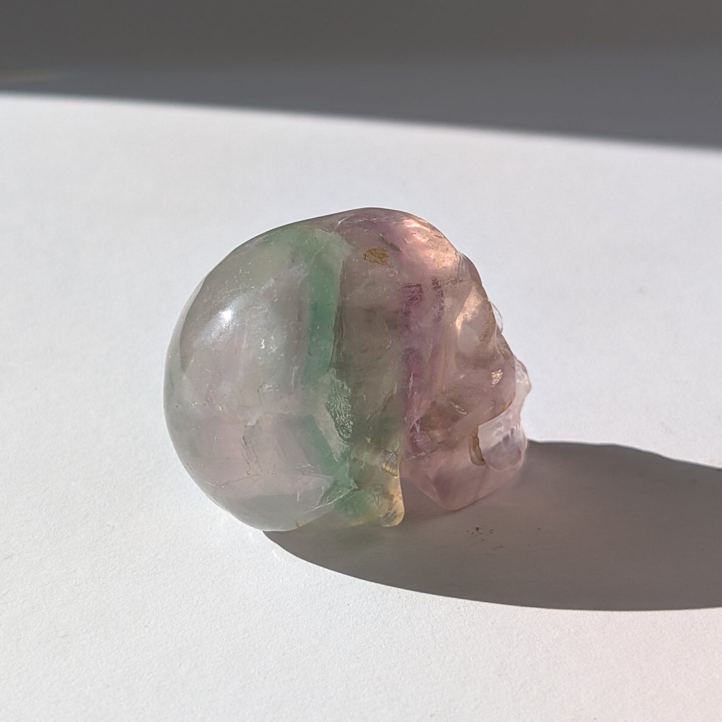 Ein 103g schwerer, handgeschnitzter Kristallschädel 'Uthar' aus durchscheinendem, grün-violettem Regenbogenfluorit.