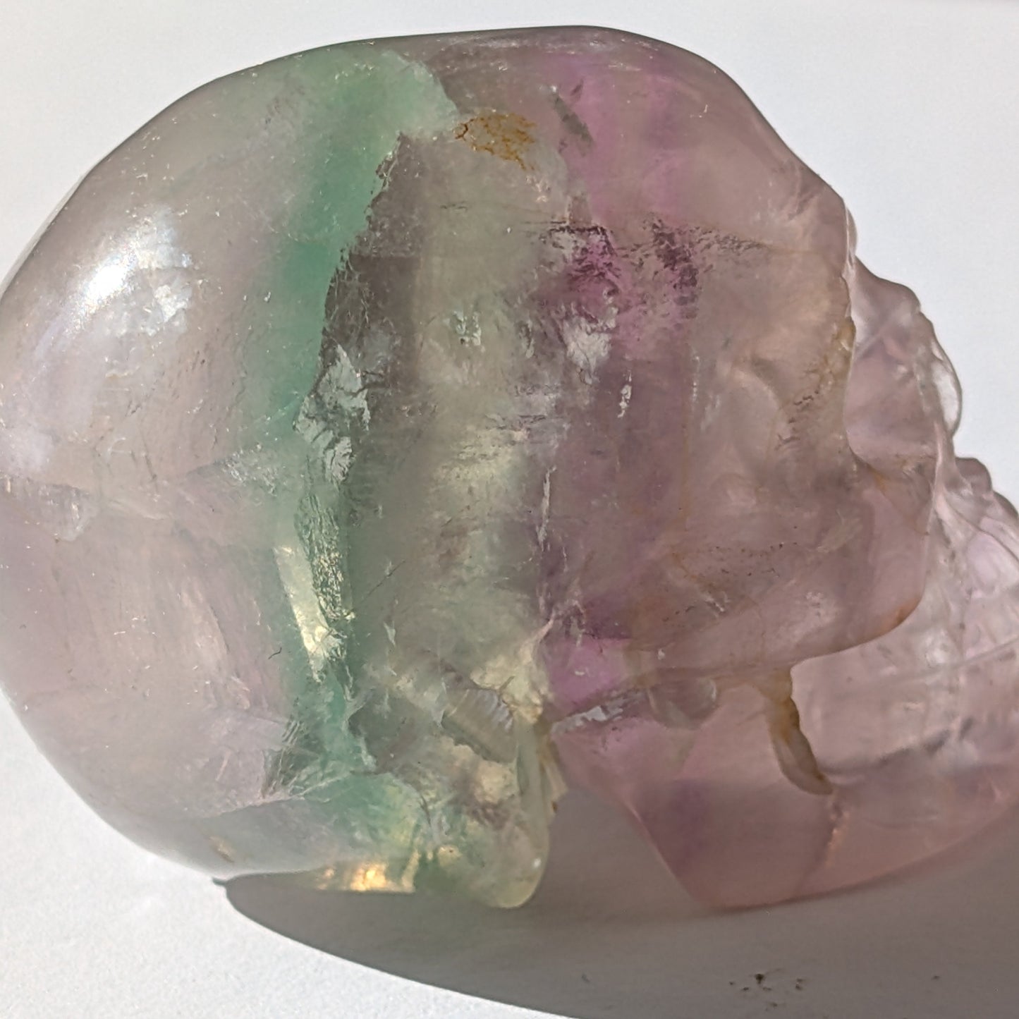 Ein 103g schwerer, handgeschnitzter Kristallschädel 'Uthar' aus durchscheinendem, grün-violettem Regenbogenfluorit.
