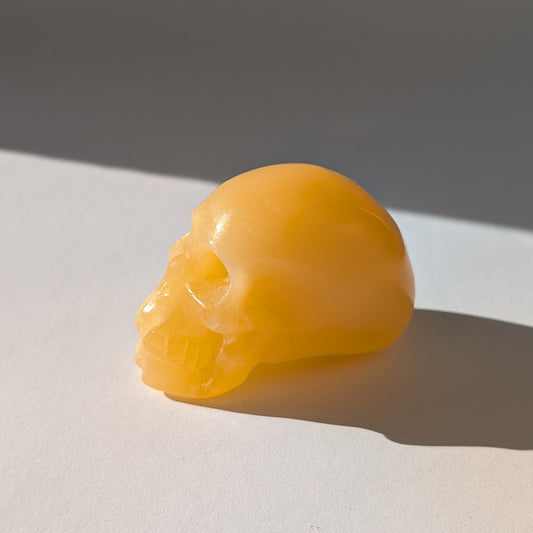 Ein 122g schwerer, handgeschnitzter Kristallschädel 'Swerdis' aus leuchtend gelbem Calcit, der sonnige Energie ausstrahlt.