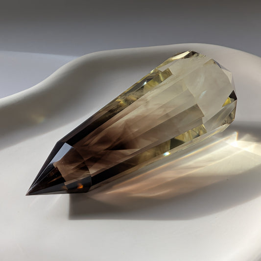 Ein 200g schwerer, doppelspitziger und facettierter Rauchquarz Stab 'Der Alchemistenstab' mit inneren Phantomen, der im Licht leuchtet.