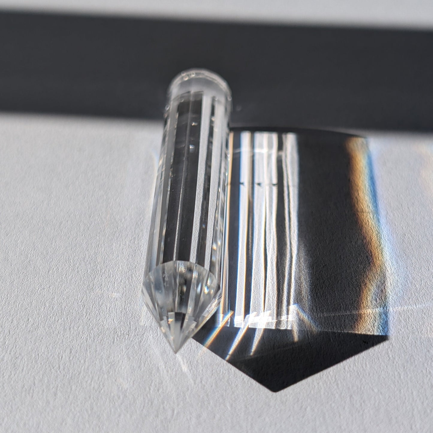 Ein 24-fach gerillter (fluted) Heilerstab aus wasserklarem Bergkristall (50g), der Licht reflektiert.