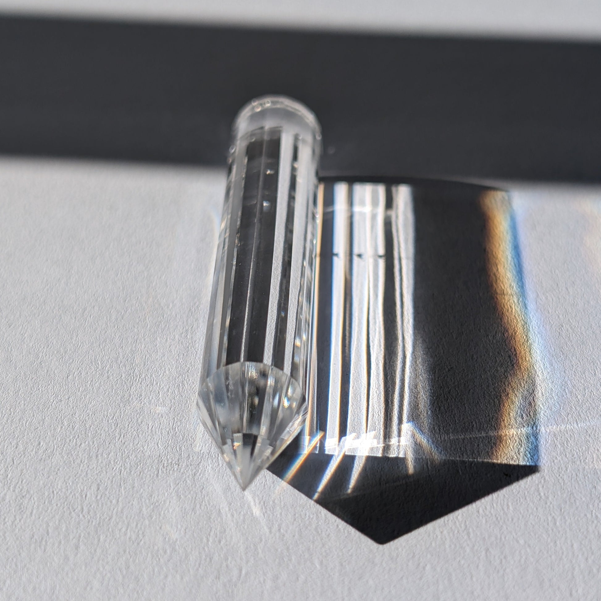 Ein 24-fach gerillter (fluted) Heilerstab aus wasserklarem Bergkristall (50g), der Licht reflektiert.