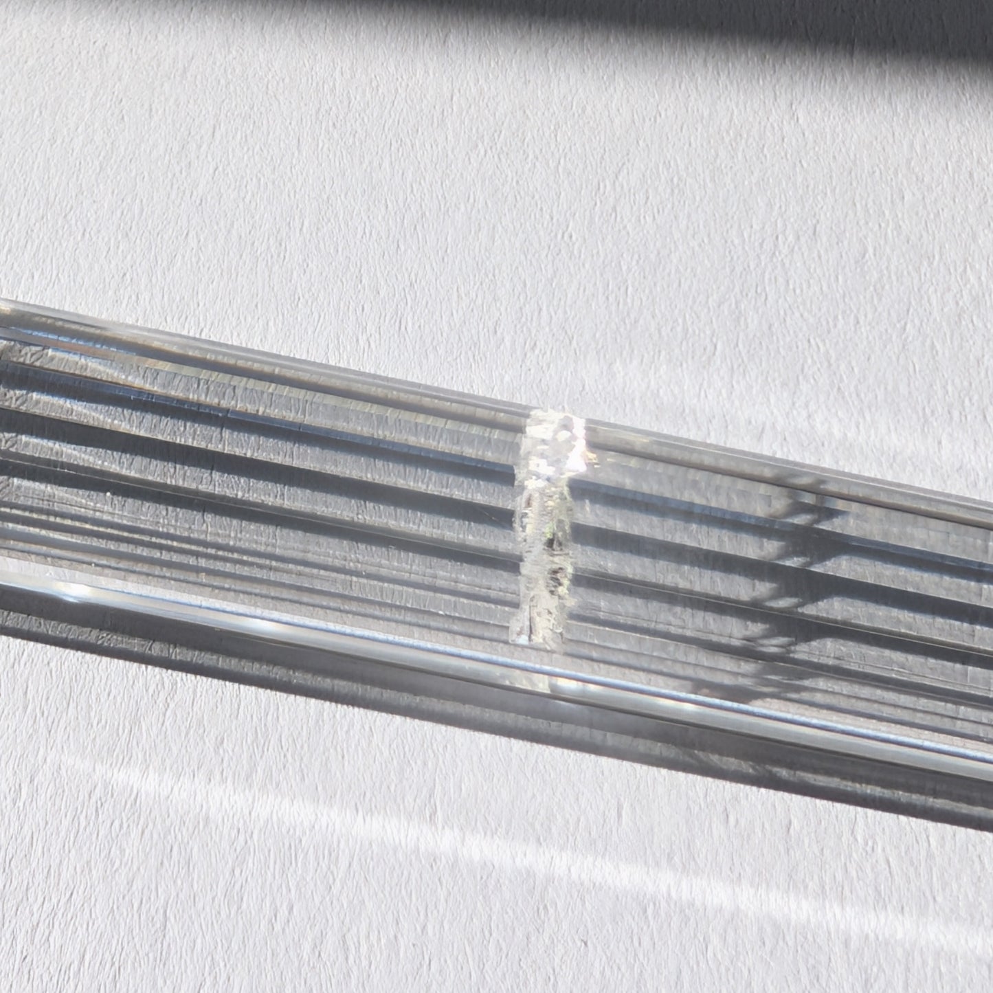 Ein 24-fach gerillter (fluted) Heilerstab aus wasserklarem Bergkristall (59g) im Licht.