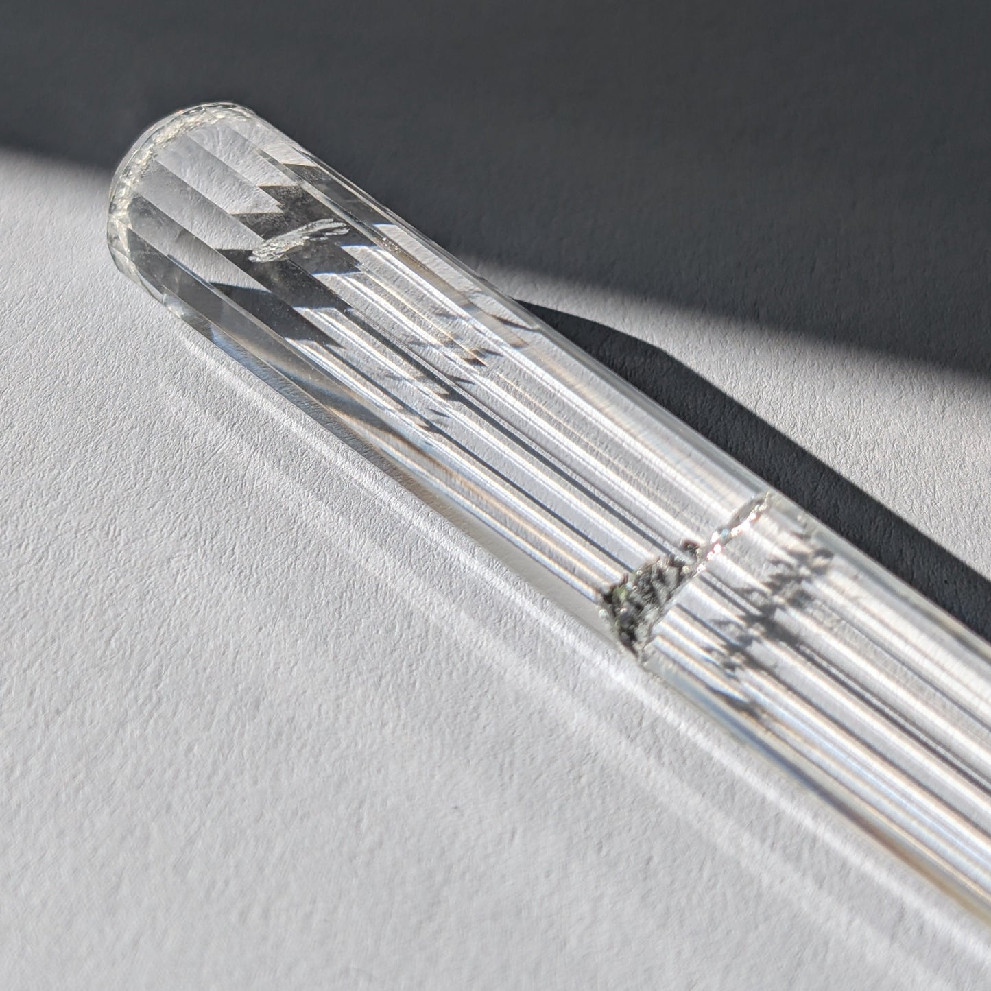 Ein 24-fach gerillter (fluted) Heilerstab aus wasserklarem Bergkristall (59g) im Licht.