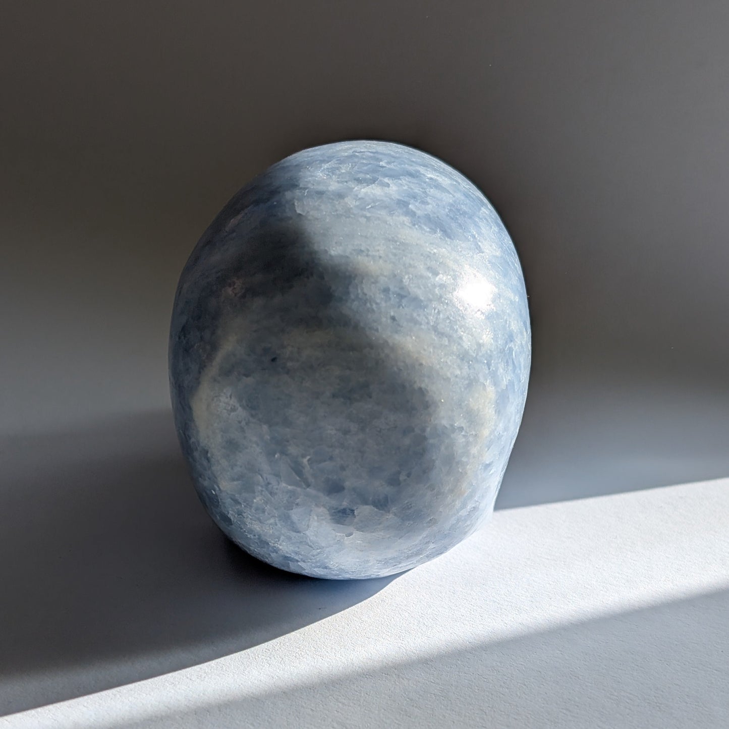 Ein 660g schwerer, handgeschnitzter Kristallschädel 'Hulu' aus zartblauem bis weißem Anhydrit, der eine friedvolle Energie ausstrahlt.