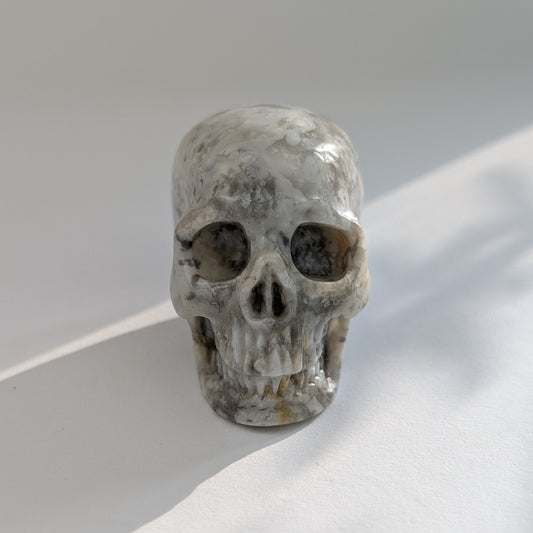 Ein 78g schwerer, handgeschnitzter Kristallschädel 'Tanard' aus Blumenachat mit zarten, blütenartigen Einschlüssen.