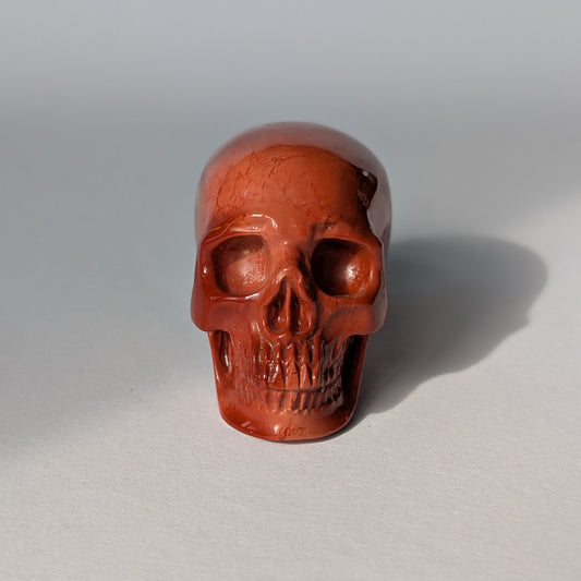 Ein 81g schwerer, handgeschnitzter Kristallschädel 'Yria' aus tiefrotem Jaspis mit einer hochglanzpolierten Oberfläche.