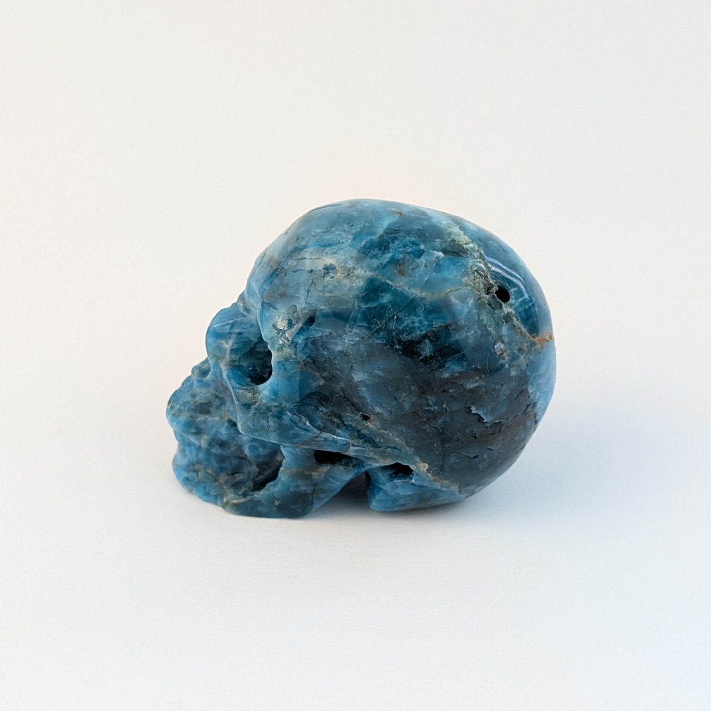 Ein 85g schwerer, handgeschnitzter Kristallschädel 'Sergil' aus leuchtend blau-grünem Apatit, der eine motivierende Energie ausstrahlt.