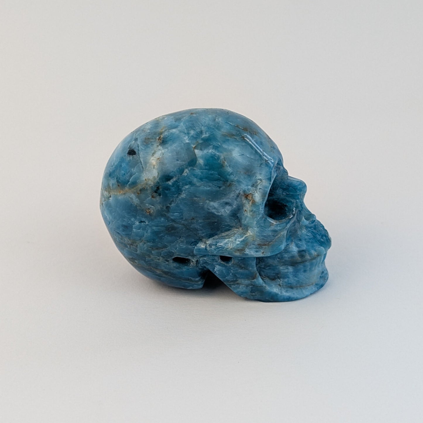 Ein 85g schwerer, handgeschnitzter Kristallschädel 'Sergil' aus leuchtend blau-grünem Apatit, der eine motivierende Energie ausstrahlt.