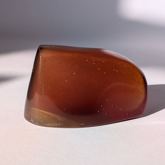 Ein großer, polierter Bicolor-Bernstein 'Die sanfte Flamme der Vorzeit', der sanft von tiefem Rot in einen goldenen Cognac-Ton übergeht.