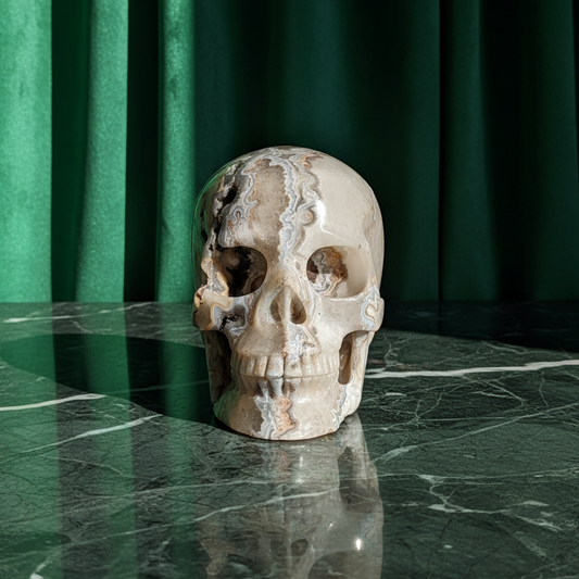 Ein monumentaler, 1292g schwerer Kristallschädel 'Der Wächter der Freude' aus Crazy Lace Achat mit hypnotischen Mustern und einer großen, offenen Druzy-Geode am Hinterkopf.