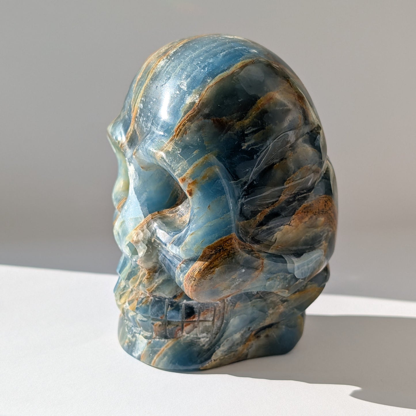 Ein monumentaler, 1654g schwerer Kristallschädel 'Istari' aus ozeanblauem Onyx mit erdigen Bändern, als Teil einer limitierten, auf Bali gefertigten Meister-Edition.