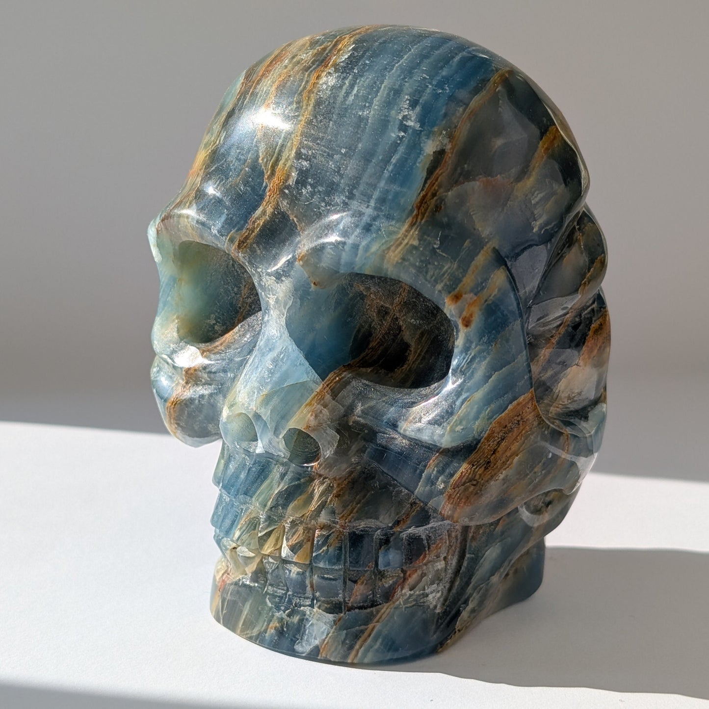 Ein monumentaler, 1654g schwerer Kristallschädel 'Istari' aus ozeanblauem Onyx mit erdigen Bändern, als Teil einer limitierten, auf Bali gefertigten Meister-Edition.