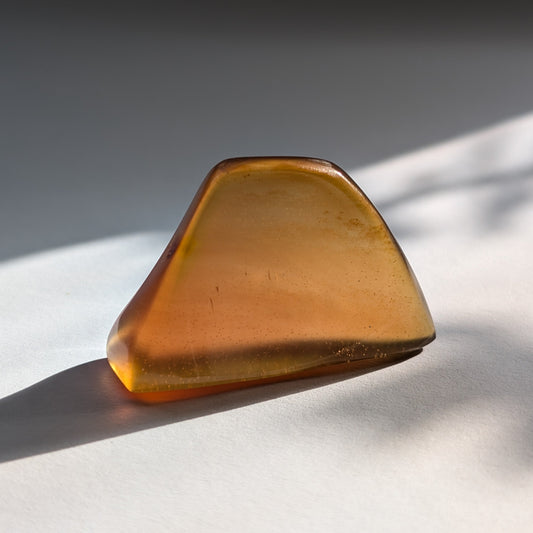 Ein polierter Bicolor-Bernstein 'Herz der Sommersonne' in natürlicher Freiform, der von Cognac-braun zu leuchtendem Sonnengelb übergeht.