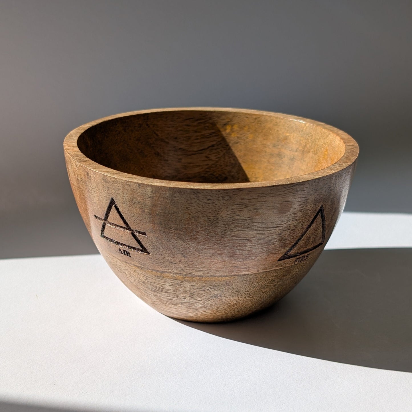 Eine handgefertigte Ritualschale 'Altar der Elemente' aus Mangoholz mit eingravierten Symbolen der Vier Elemente.