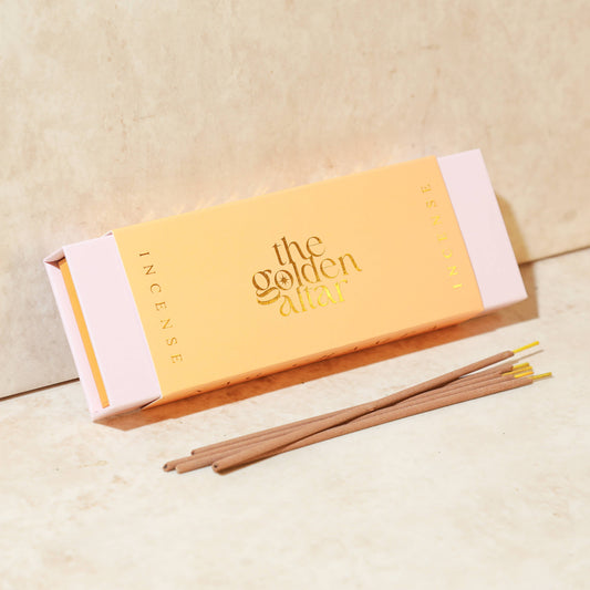 Eine pfirsichfarbene Box von The Golden Altar mit 30 Nag Champa Räucherstäbchen, die daneben liegen.