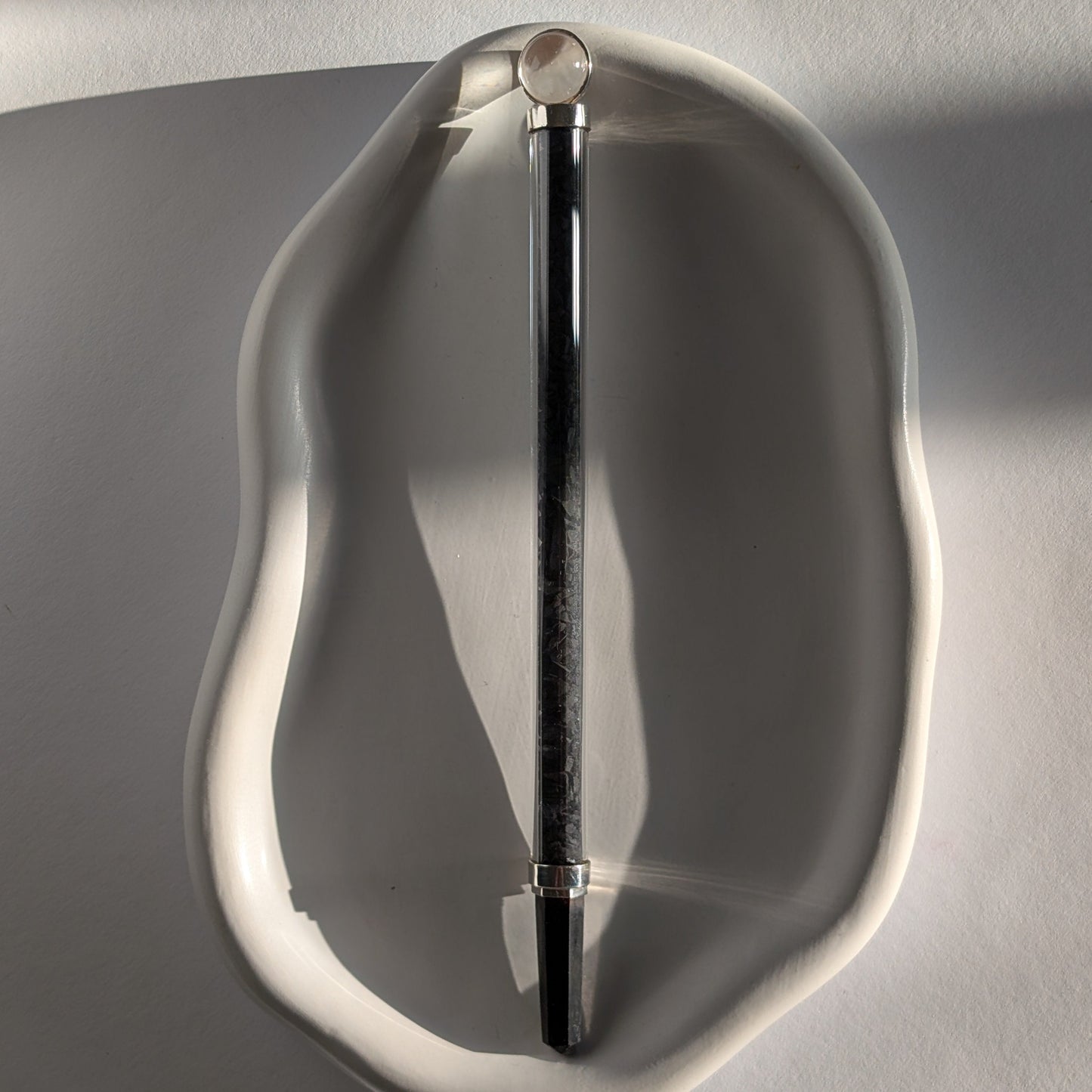 Eleganter Generatorstab mit Schungit-Füllung, Quarzkugel und schwarzer Spitze in hellem Licht.