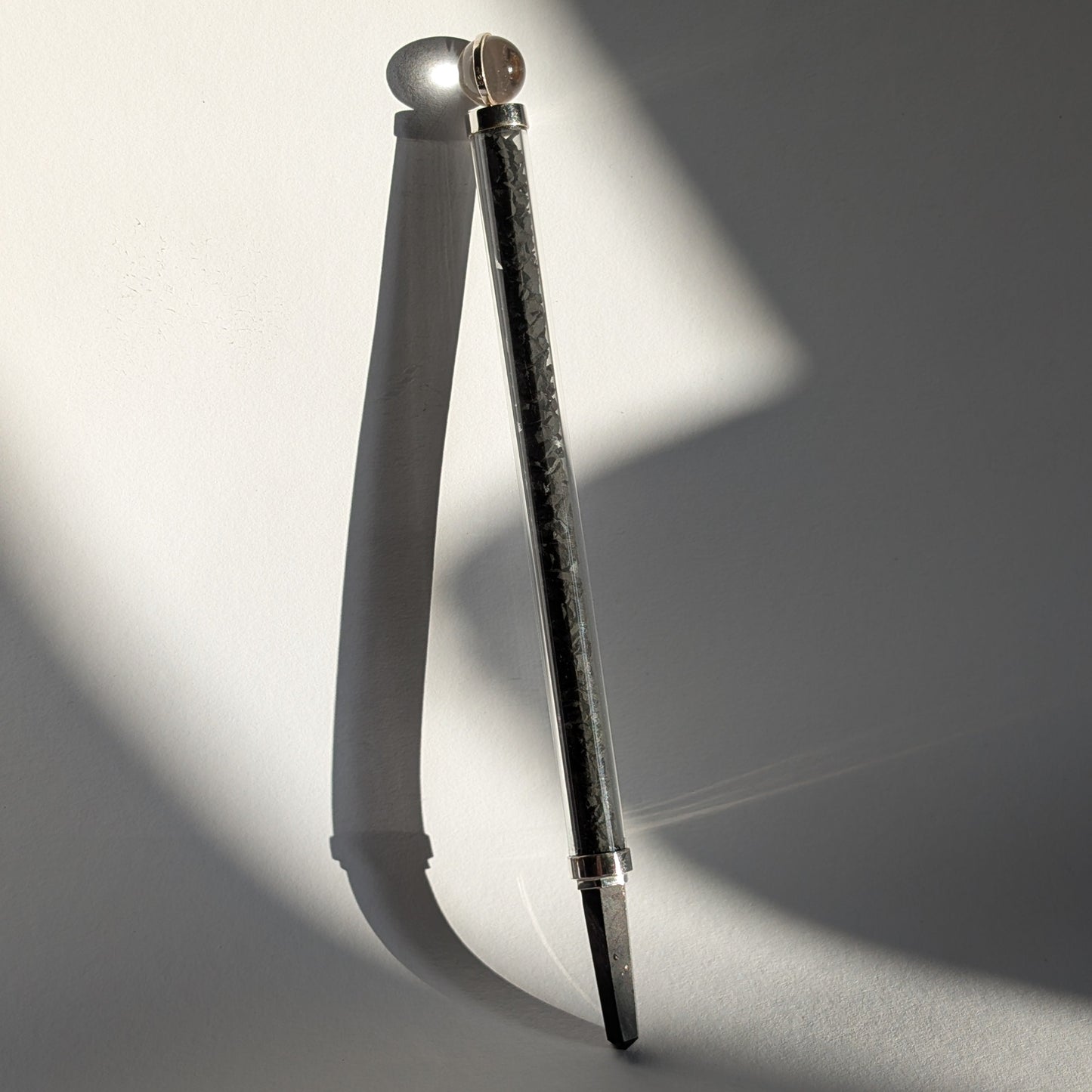 Eleganter Generatorstab mit Schungit-Füllung, Quarzkugel und schwarzer Spitze in hellem Licht.
