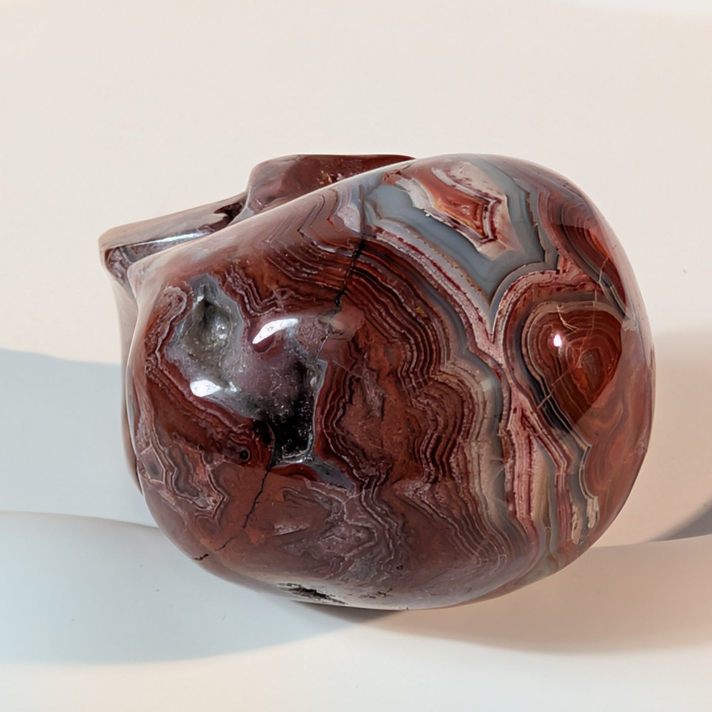 Gefährlich wirkender Kristallschädel Bjarny aus wild gebändertem Achat 84g mit chaotischen, tiefroten und grauen Adern