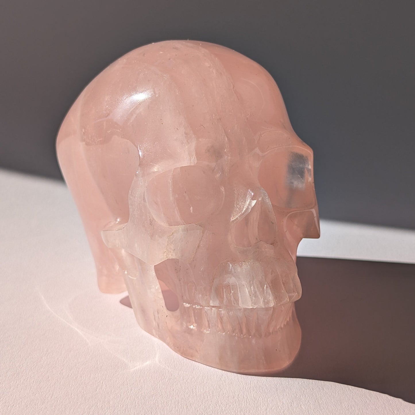 Großer Kristallschädel (1.16kg) aus sanft leuchtendem Rosenquarz im Seitenprofil.