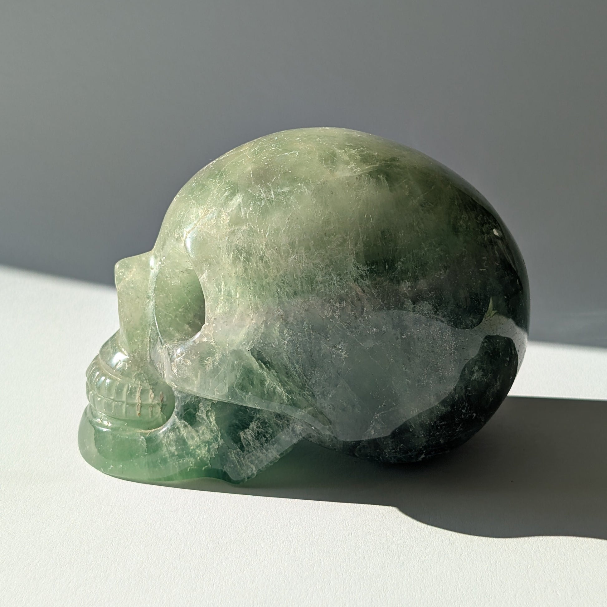 Großer Kristallschädel "Gulkar" (fast 2kg) aus leuchtend grünem Fluorit, seitlich beleuchtet.