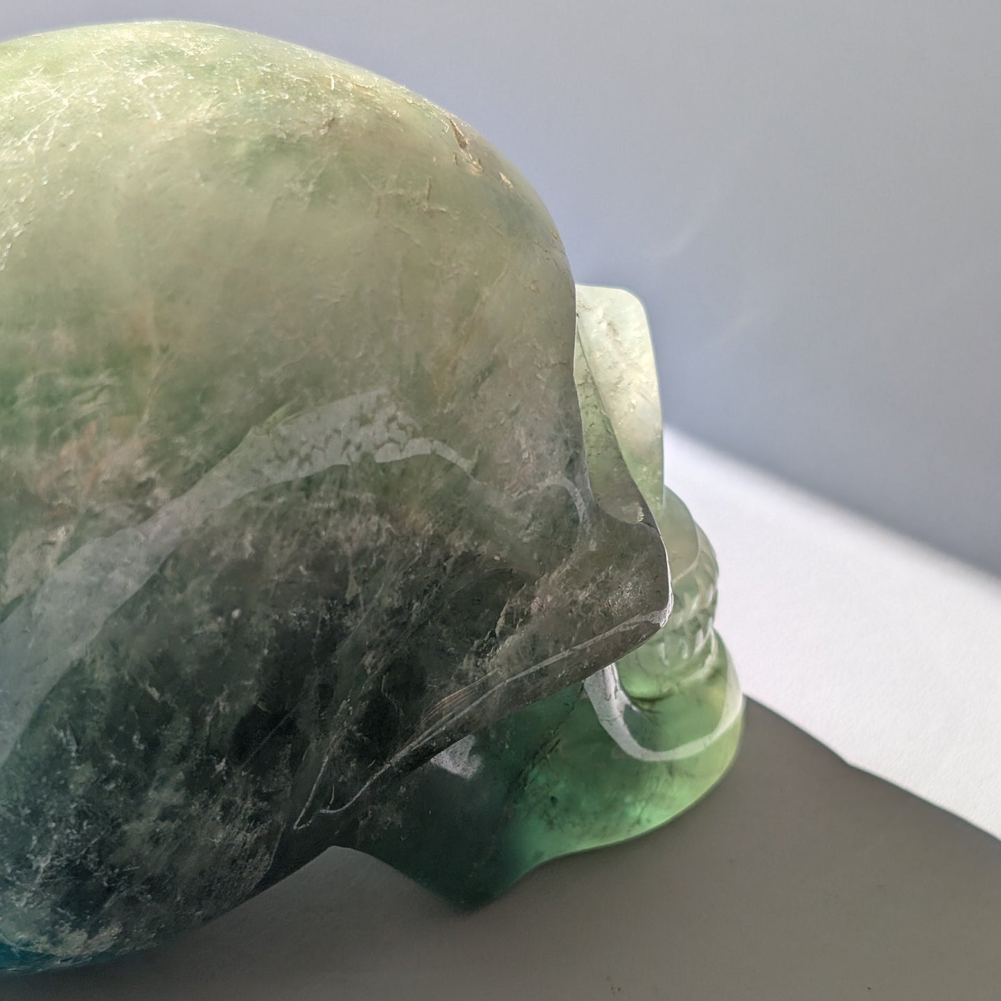 Großer Kristallschädel "Gulkar" (fast 2kg) aus leuchtend grünem Fluorit, seitlich beleuchtet.