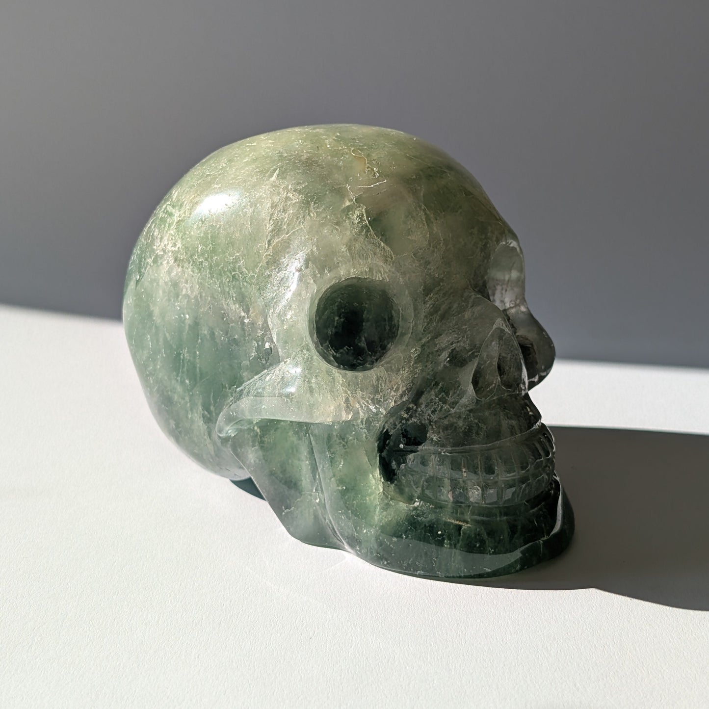 Großer Kristallschädel "Gulkar" (fast 2kg) aus leuchtend grünem Fluorit, seitlich beleuchtet.