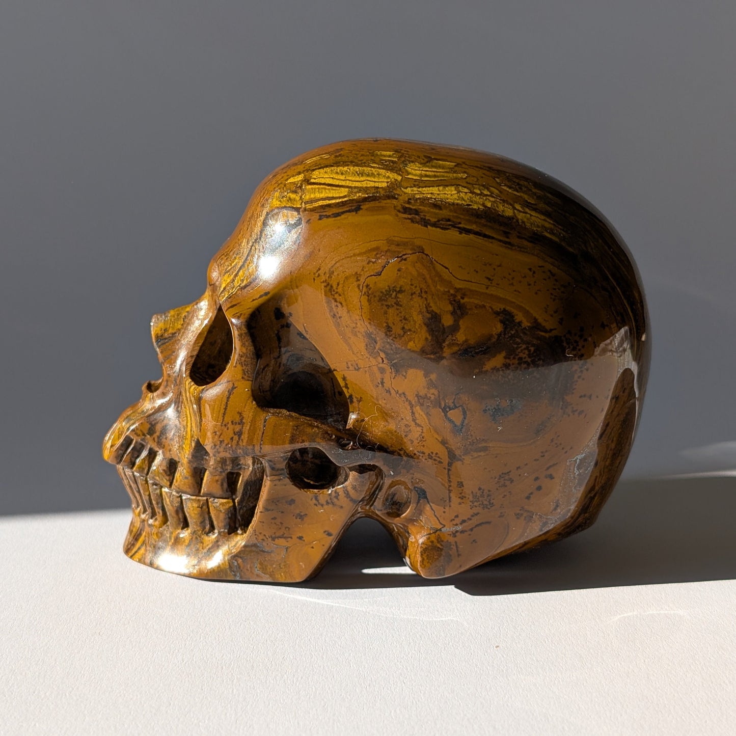 Großer Kristallschädel "Mekil" (1.32kg) aus gebändertem Tigereisen mit Goldschimmer.