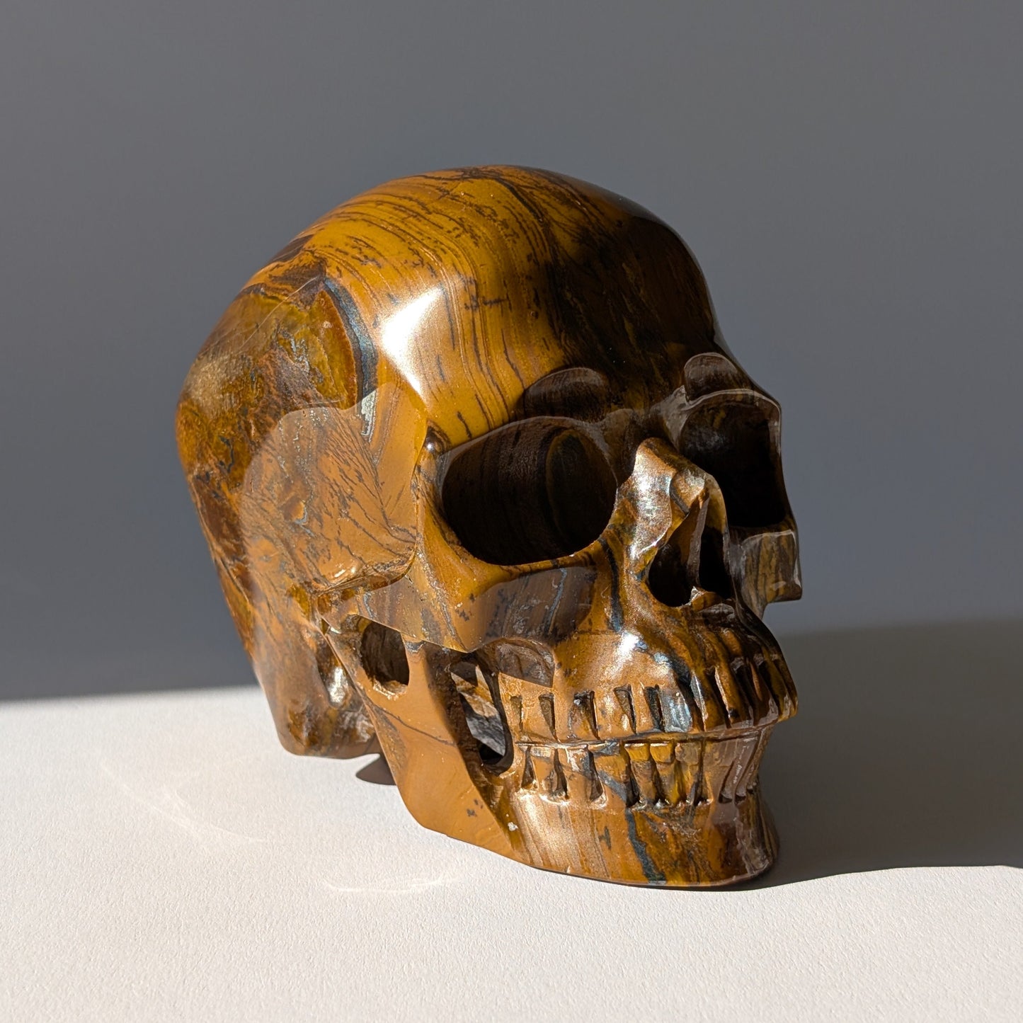 Großer Kristallschädel "Mekil" (1.32kg) aus gebändertem Tigereisen mit Goldschimmer.