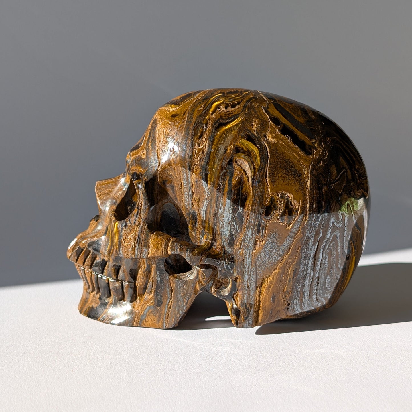 Großer Kristallschädel "Roban" (1.55kg) aus hochwertigem Tigereisen mit starkem Goldschimmer.